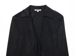 Détail d'une chemise noire aspect suédine avec col à lacets et étiquette de marque