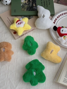 Flat lay of assorted plush Christmas ornaments including trees and snowmen on white fabric