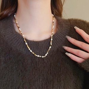 Detail of freshwater pearl and agate beaded necklace on model in brown sweater