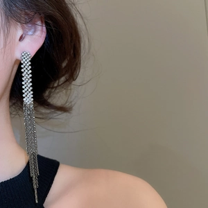 Close-up of elegant silver tassel earrings with shimmering rhinestones worn by a model
