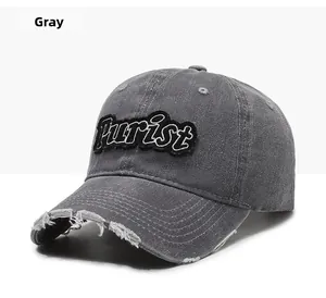 Detail of gray distressed baseball cap featuring black Purist embroidery and worn brim