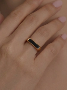 Close-up of minimalist gold plated ring with rectangular black enamel on finger