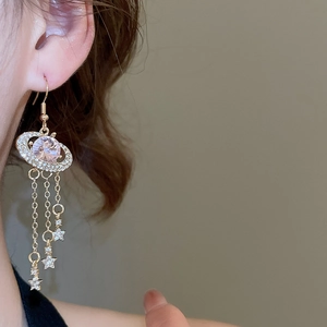 Close-up of dangling star tassels with pink crystal stone and gold finish on earring