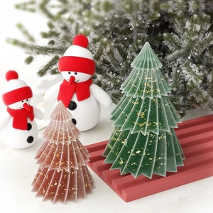 Künstlerische Origami-Weihnachtsbaumkerzen mit Goldflocken auf festlichem Winterhintergrund