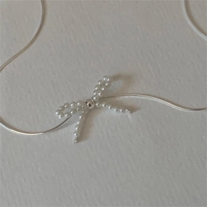 Macro detail of 925 sterling silver snake chain and elegant pearl bow pendant