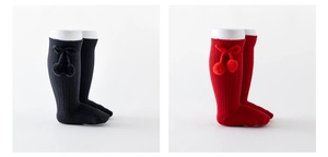 Detail of ribbed knit baby knee high socks featuring fuzzy pom-pom bow accents