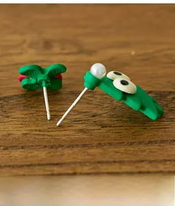 Detailed view of green resin crocodile earrings with pearl and S925 silver needle marks