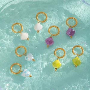 Lot de boucles d'oreilles dorées avec pendentifs coquillages en céramique sur fond bleu