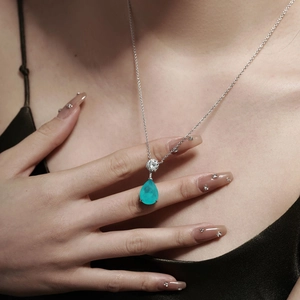 Detail of pear-shaped paraiba tourmaline pendant with silver chain and emerald zircon accents