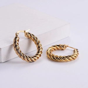 Polished golden twisted hoop earrings with elegant rope texture on minimalist background