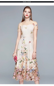 Detail of colorful floral embroidery and sheer mesh texture on an elegant beige dress