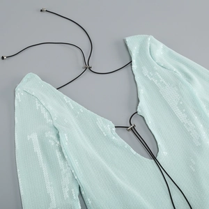 Detalle de vestido de lentejuelas verde menta con cordón negro y cuentas plateadas