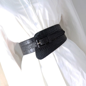 Detail of black crocodile texture corset belt with silver square buckle on a white shirt