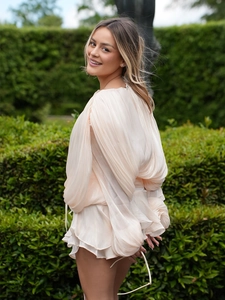 Detail of the pleated lantern sleeves and layered wavy hem on a cream chiffon dress