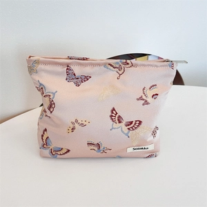 Detailed view of colorful butterfly embroidery on a pink fabric shoulder bag