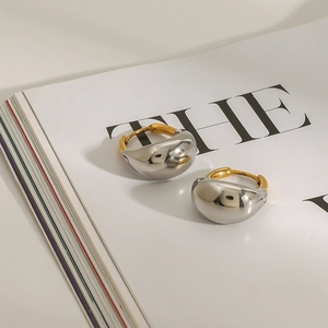French style two-tone 18K gold and silver stainless steel chunky hoop earrings on a book