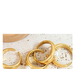 Detailed macro view of four golden pearl rings set on a textured beige stone background