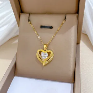 Close-up of golden hollow double heart pendant with cubic zirconia and love engraving