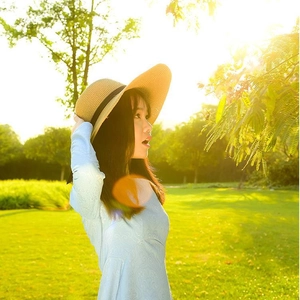 Detail of straw hat texture and light blue dress on a sunny summer outdoor park