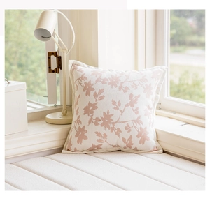 Detail of pink leaf pattern cushion cover on a cozy window seat in natural light