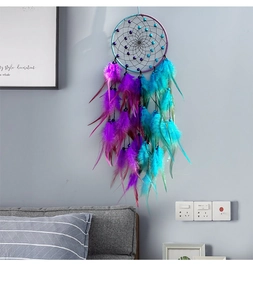 Detail of dream catcher with purple and teal feathers hanging on a bedroom wall