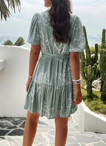 Back view of a green vacation dress with white geometric print and ruffled hemline