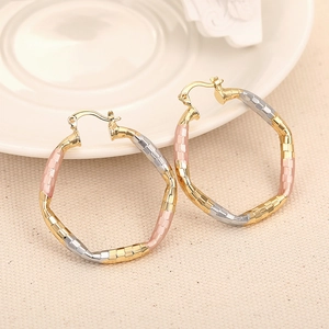 Detailed view of tri-color gold hoop earrings with woven texture and wavy design