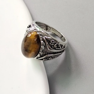 Detailed close-up of a vintage men's ring with oval tiger eye stone and ornate silver engraving