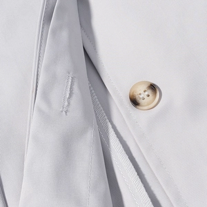 Detail of light gray twill suit jacket showing a gradient button and neat stitching