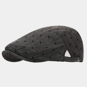 Close-up of grey herringbone flat cap featuring laser-cut ventilation holes and side buckle