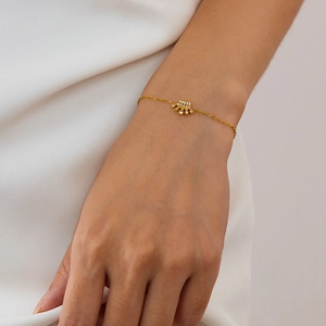 Close-up of a gold palm pendant bracelet with diamonds on a model's wrist