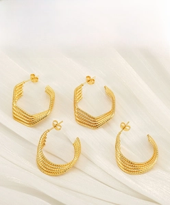 Detail of 18k gold-plated irregular U-shaped earrings with fine textured metallic finish
