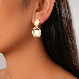 Détail d'une boucle d'oreille dorée vintage avec pierres d'opale et cristaux brillants