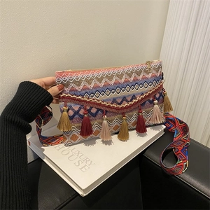 Detail of bohemian woven crossbody bag with colorful tassels and geometric wide strap