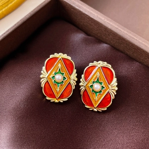 Detail of vintage enamel oval earrings with faux pearls on premium brown silk fabric