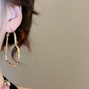 Close-up of a gold heart-shaped twisted earring worn on the ear showing metallic luster