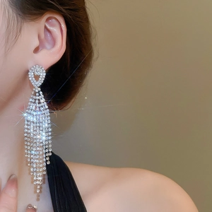 Macro side view of sparkling rhinestone tassel drop earrings worn by a model