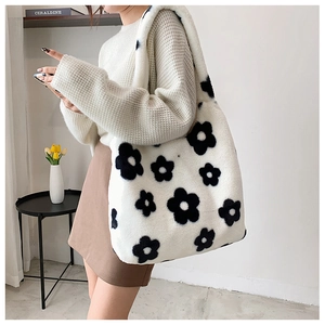 Detail view of large white plush tote bag with black floral pattern on model shoulder