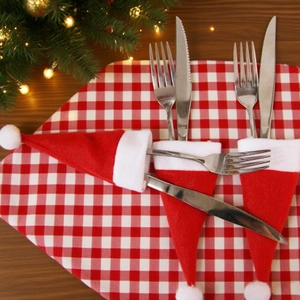 Mini Santa hat cutlery holders with knives and forks on festive table setting