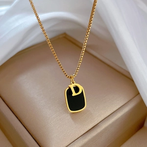 Macro view of gold-plated D-letter pendant necklace on a beige jewelry storage box