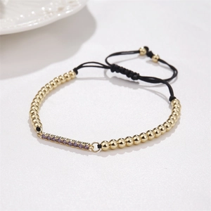 Adjustable gold plated bracelet with purple cubic zirconia bar and woven black rope