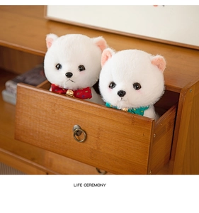 Detail of two white Pomeranian plush dogs with polka dot bows in a vintage wooden drawer