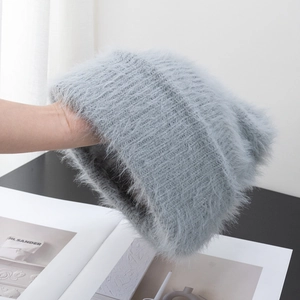 Close-up of light gray fuzzy knit beanie showing soft long plush fibers and ribbed texture
