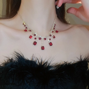 Detail view of silver necklace featuring red square gemstones and crystal fringe on a model
