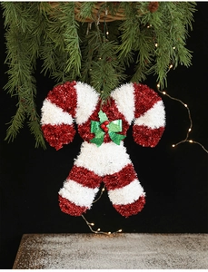 Close-up of candy cane Christmas ornaments with ribbon bows on a snowy tree branch
