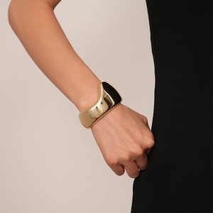 Detailed side view of glossy gold irregular open bangle on woman's wrist