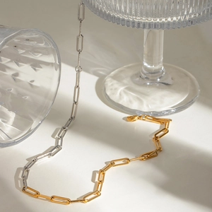 Two-tone gold and silver paperclip chain necklace with lobster clasp on glass