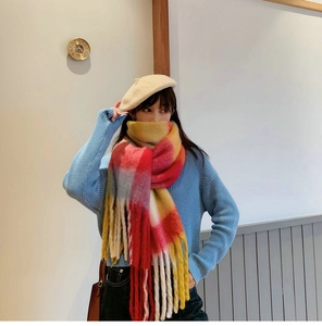 Detailed view of the colorful plaid scarf featuring long tassels and soft knit texture