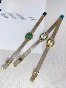 Three vintage oval quartz watches with gold mesh straps and multi-color dials shown in flat lay