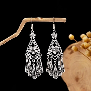 Detail of vintage bohemian hollow earrings with silver tassels on a natural branch